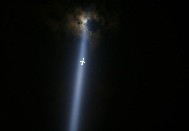 Самолёт, летящий в свете прожектора на церемонии памяти жертв терракта в Нью-Йорке

