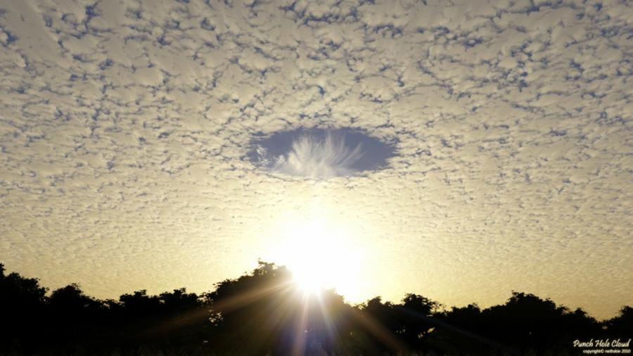 This rare effect can be seen in cirro-Cumulus clouds — large circular gap that is called a Fallstreak. Hole in the clouds caused by falling ice crystals.

Ice crystals can form in the higher clouds or the condensation trail of the aircraft flown. Usually they are produced by the plane passing through such a cloud layer. In this case, if the air has a suitable temperature and moisture content, the falling crystals will absorb water from the air and grow.

For this to happen, the water must be so cold that freezing it needs only a suitable surface. Loss of moisture in the air increases the evaporation rate of water droplets in the cloud, and they are scattered, forming a hole.
Translated by «Yandex.Translator»